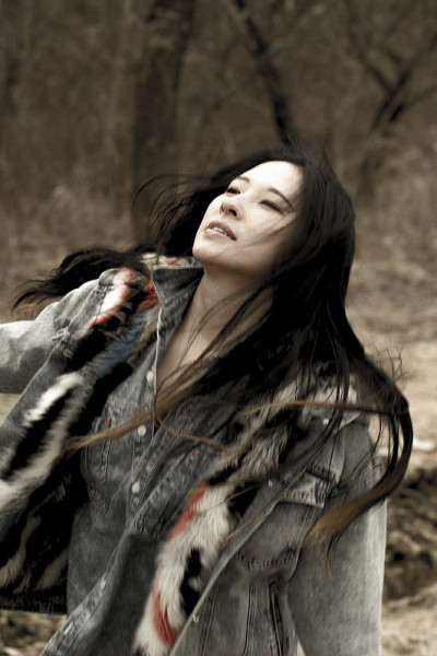 在天然森林中，一位长发女子凝视着天空。