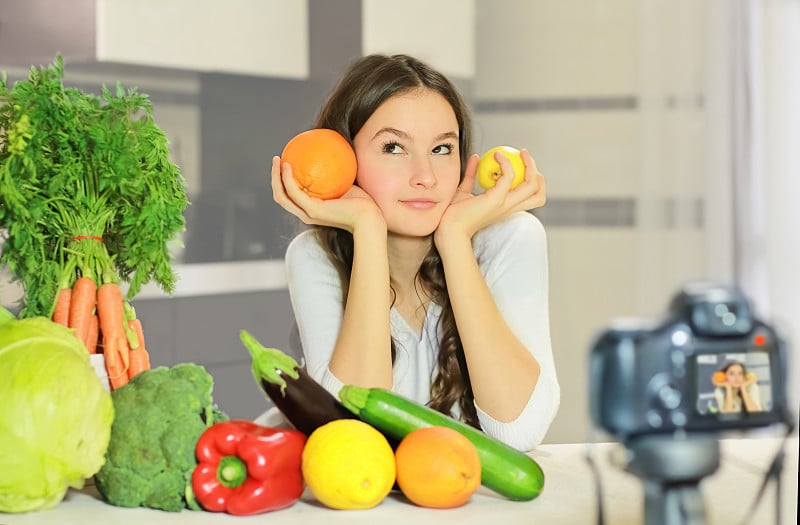 一位年轻的博主向她的粉丝们解释如何健康饮食。向青年人宣传健康饮食习惯、维生素和热量的重要性的概念。