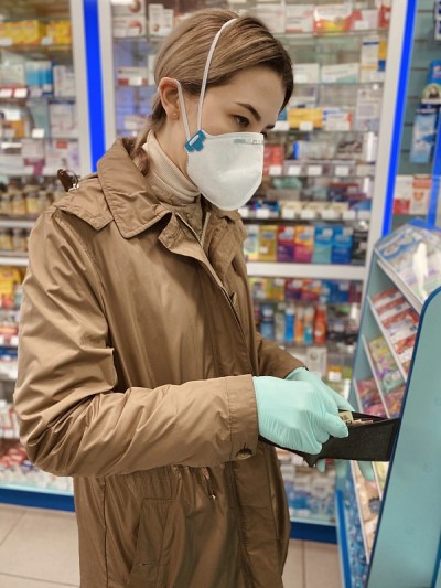 戴着防冠状病毒口罩和手套的女孩在超市付款。俄罗斯的年轻女性。新型冠状病毒肺炎Covid-20。女孩在