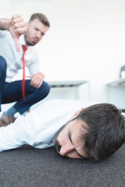 商人对疲惫不堪的同事做大拇指向下的手势