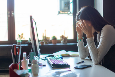 商务女性或学生在办公室使用台式电脑头痛。