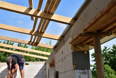 在建造房子的过程中，石匠们在屋顶下的框架上锯木头