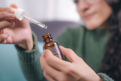年轻女子手里拿着一个容器，上面有滴管显示里面的东西。