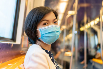 亚洲妇女戴口罩，在通勤列车上防护冠状病毒