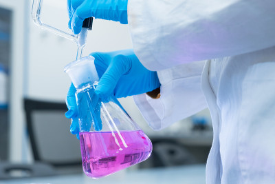 近距离观察科学家使用滴定分析法来研究水样的化学性质。科学家拿着装有粉红色溶液的锥形瓶。