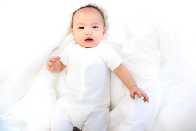 亚洲宝宝在房间里很开心。亚洲女婴躺在床上。
