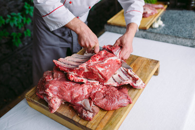 在餐馆里，一个厨师用刀切肉