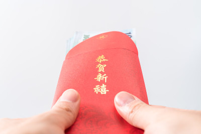 男人的手拿着中国的红包。中国新年的概念。(中文“Gōnghè xīnxǐ”的意思是“祝你财源广进”)