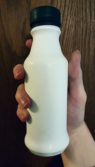 手里拿着空白的白冰沙饮料瓶