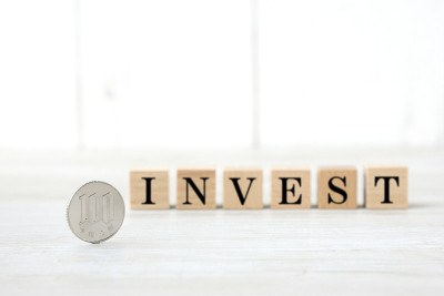 日本100日元硬币和带有INVEST字样的木块