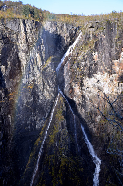 Scenery with long norwegian waterfall and rainbow