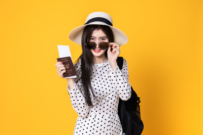 夏日休闲装的女游客。亚洲微笑女子。以黄色为背景出国旅行的乘客。一个亚洲女人要去度暑假。旅行有趣的旅行