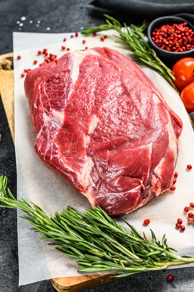 在木砧板上切的生牛胸肉。黑安格斯牛肉。黑色背景。俯视图