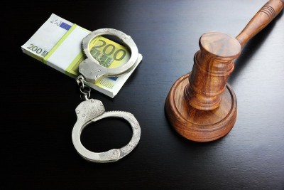 黑桌子上的法官木槌、手铐和欧元现金