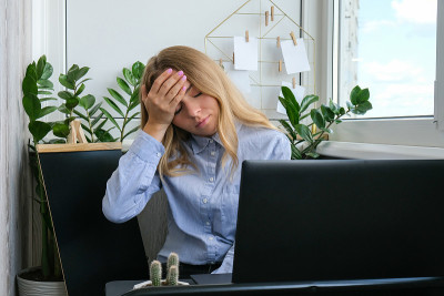 疲惫困倦的年轻白人女工在办公场所。过度工作和睡眠不足。女商人与金融危机。自由职业者的萧条。看着笔记本