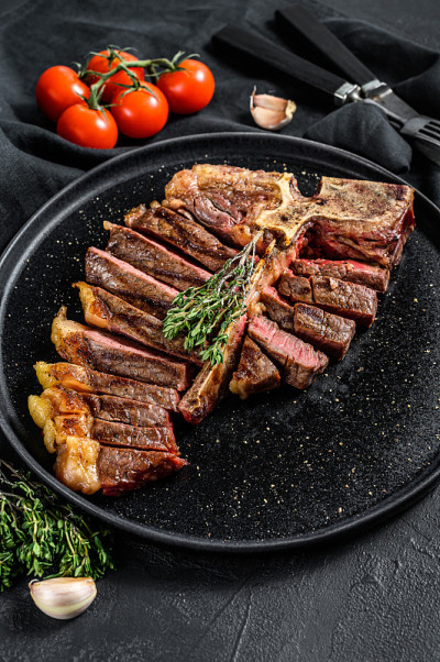 在切菜板上烤的上等牛排。煮熟的牛肉肉。白色木制背景。俯视图