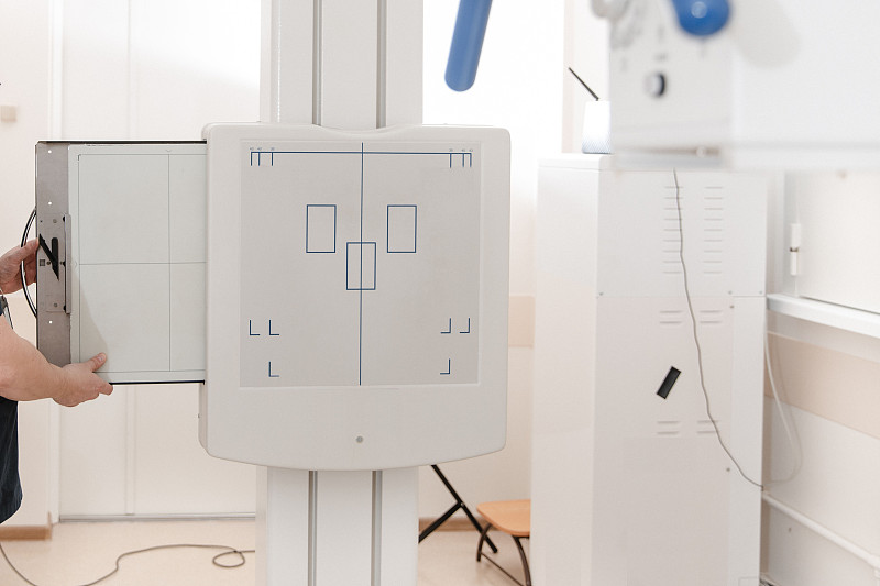 现代化医院x光科。放射线室配有扫描仪和空床。技术员在调整x光机。现代临床办公室扫描胸、心、肺