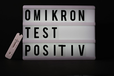 在一块刻有“Omikron检测阳性”字样的光板旁边，放置着一份新冠抗原快速检测阳性的纸条