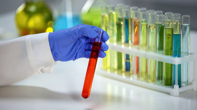 药剂师用橙色液体、染料、洗涤剂检查试管