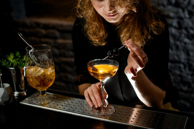女调酒师用现成的浆果装饰酒杯