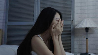 女人感到沮丧，坐在床上