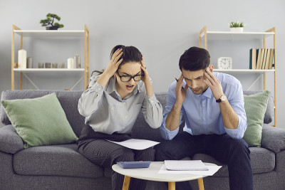 震惊的年轻夫妇看着抵押贷款支付更改通知或巨大的公用事业账单