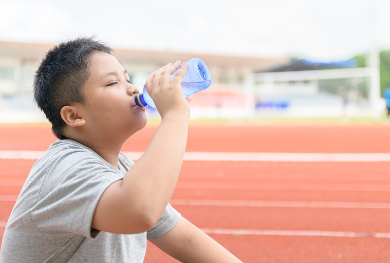 亚洲男孩喝塑料瓶里的水