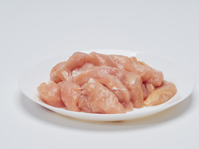 将一小块生鸡肉堆在一个白色盘子里