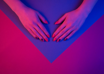 女性的手与复古波浪时尚美甲在霓虹灯。