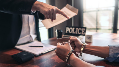 戴手铐的犯罪嫌疑人在审讯室接受警察讯问，刑法概念