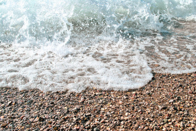 卵石滩和海浪俯视图。柔和的海浪和多岩石的海岸，选择性聚焦