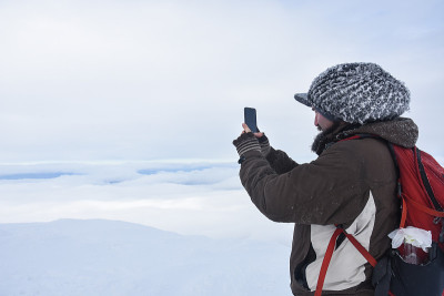 用智能手机拍摄雪山的徒步旅行者
