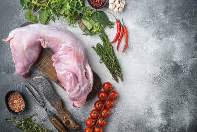 生兔肉配上新鲜的蔬菜、香草和香料，在灰色的石头背景上，顶视图平铺，带有文本的复制空间