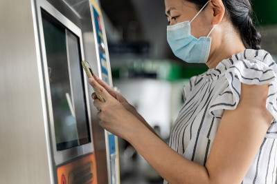 戴口罩的女子在自动售票机购买地铁车票