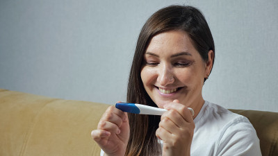 年轻女子高兴地看着验孕棒的特写镜头