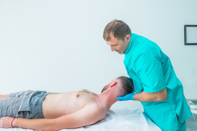 男患者接受治疗师按摩。一个脊椎按摩师在医务室里给病人伸直脖子。神经系统体格检查。整骨疗法、按摩、理疗