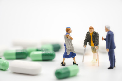 折断腿的老人、护士和医院经理在白色的背景上带着医药药丸、胶囊和药片。医院概念-形象