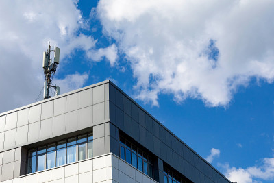 城市环境中的4G、5G发射器。在多云的天空下，办公大楼屋顶上装有发射天线的蜂窝基站。