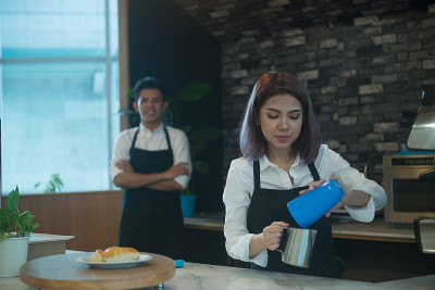 亚洲女性咖啡店老板准备饮料的肖像