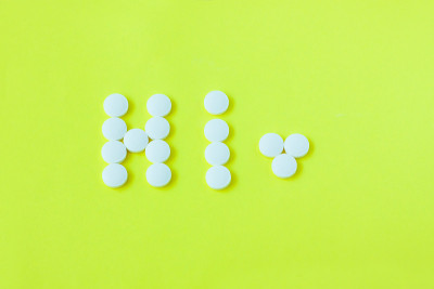 黄色背景上的“嗨”字形状的药丸。平躺，俯视图，极简风格。