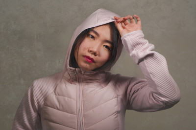 美丽和时尚风格孤立的年轻美丽和凉爽的亚洲中国女学生在粉红色兜帽冬季夹克孤立在垃圾摇滚工作室背景肖像