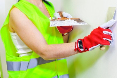 女建筑工人拿着抹刀靠近墙壁
