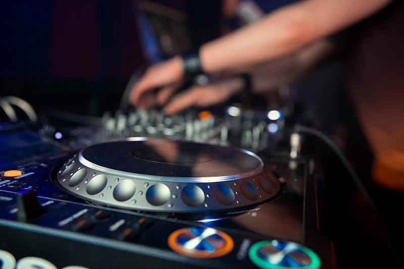 夜总会里的Dj在派对上混音。在背景激光显示