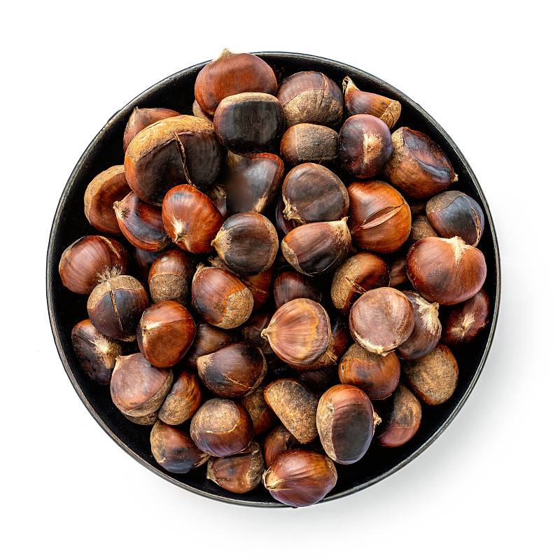 Roasted chestnuts on a round plate  isolated on wh