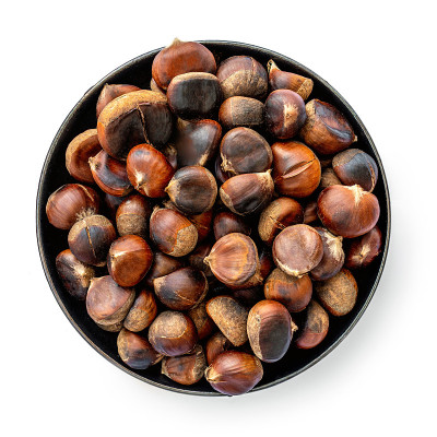 Roasted chestnuts on a round plate  isolated on wh