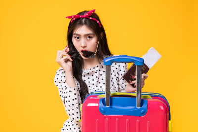 夏日休闲装的女游客。亚洲微笑女子。以黄色为背景出国旅行的乘客。一个亚洲女人要去度暑假。旅行有趣的旅行