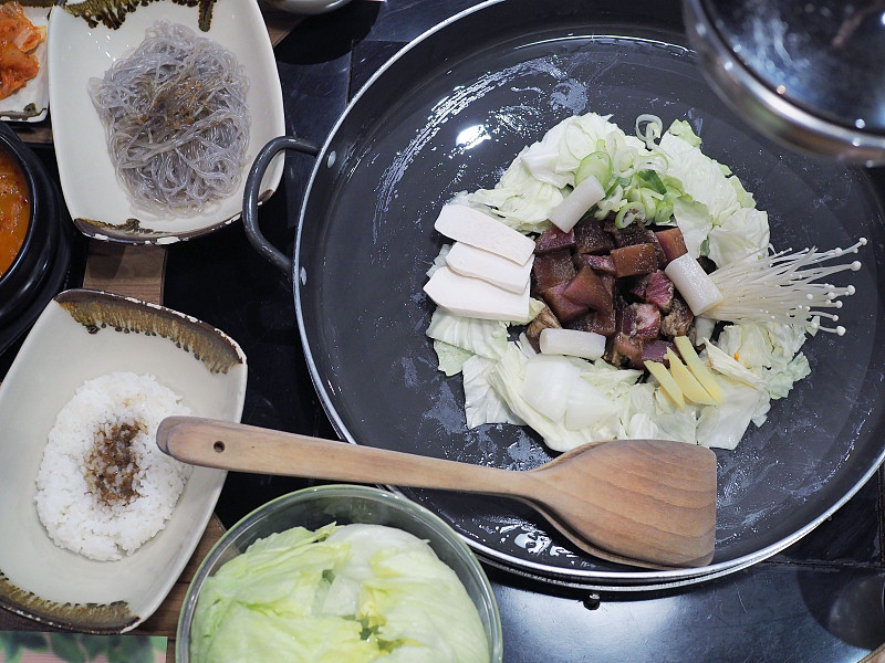 大型金属平底锅烹煮韩式烤肉，用蔬菜炒黑田肉，面条和米饭拌韩式酱汁。