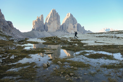 一名男子徒步旅行，欣赏意大利Dolomites地区的Drei Zinnen山。群山倒映在小桨里。荒凉