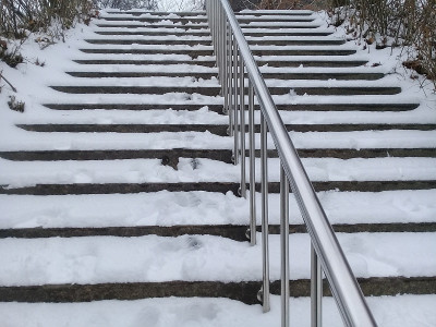 积雪覆盖的楼梯，配有不锈钢栏杆或扶手供行人使用