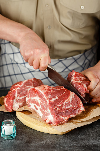 男性的手切猪肉刀的特写